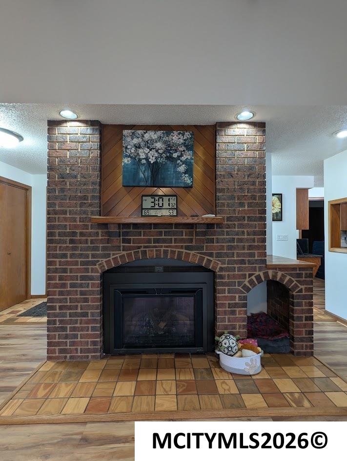 Brick fireplace with a wooden mantel, floral artwork above, and an arched brick alcove on the right; a pet bed and ball sit nearby.